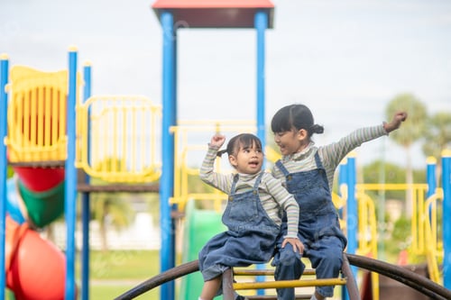Preview: Cute little girls siblings having fun on playground outdoors on a sunny summer day.