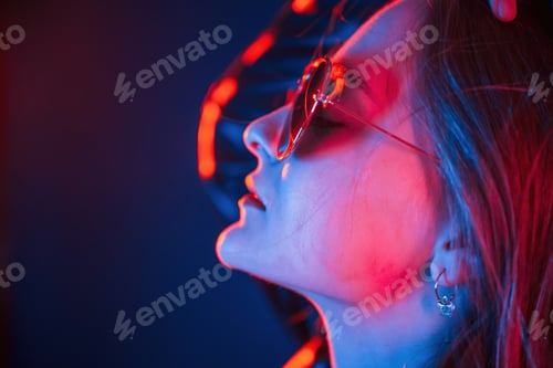 Preview: Side view, in eyewear. Cool young woman portrait in neon colors