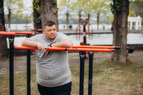 Preview: fat man drinks water after jogging in the park