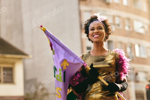 Preview: Cheerful black woman in carnival costume during Mardi Gras parade in the city.