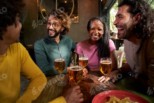 Preview: Group of hispanic people partying and drinking beer in a pub. They chat and laugh