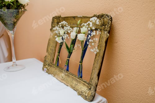 Preview: Closeup shot of an old fashioned frame with white flowers leaning on a beige wall