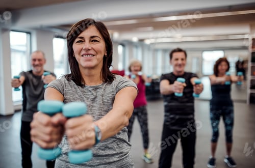 Preview: Group of cheerful seniors in gym doing exercise with dumbbells.