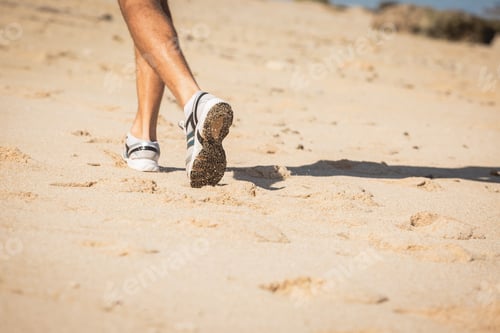 Preview: low section view of sportsman in sneakers running on sand beach