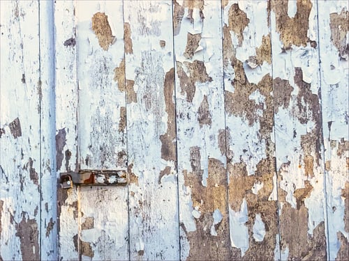 Preview: A grunge wooden facade with gate doorway that has pale blue peeling paint