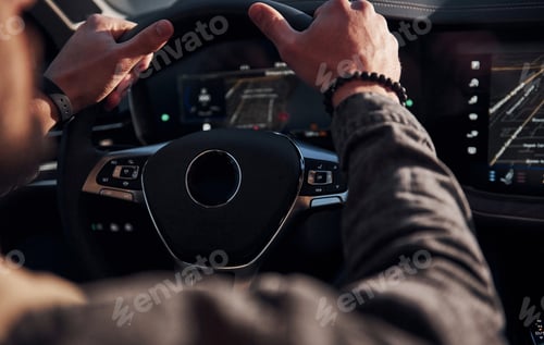 Preview: Rear view of handsome unshaved man in fashionable clothes that riding his automobile