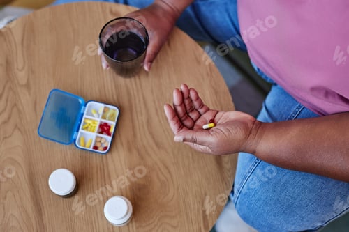 Preview: Above angle of aged African American woman in casualwear going to take pill