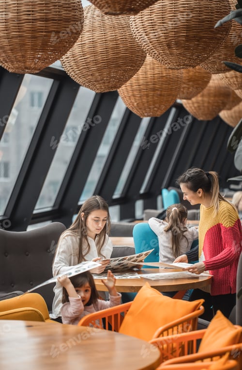 Preview: Happy young women with children sitting at table in restaurant