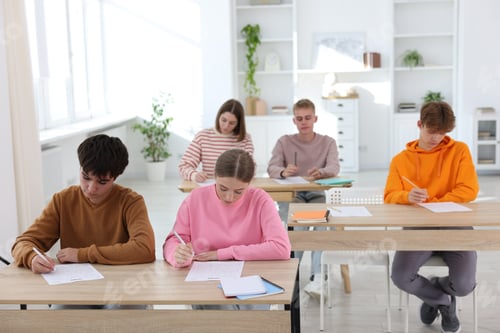 Preview: Students taking exam at wooden table indoors
