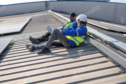 Preview: Engineer on rooftop sitting next to solar panels rest sitting relaxation after work completed