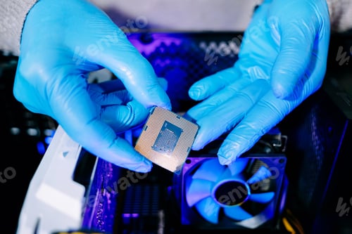 Preview: Closeup of technician with gloves installing CPU chip on motherboard near cooling fan, symbolizing