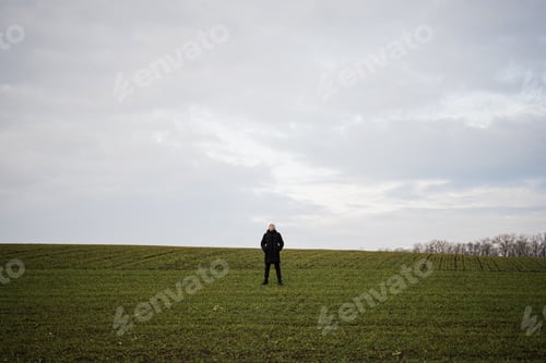 Preview: Teen boy wearing black jacket and white hat outside, enjoys in the early spring field..