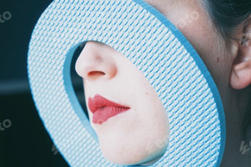 Preview: Young woman red lips behind a cover blue circle