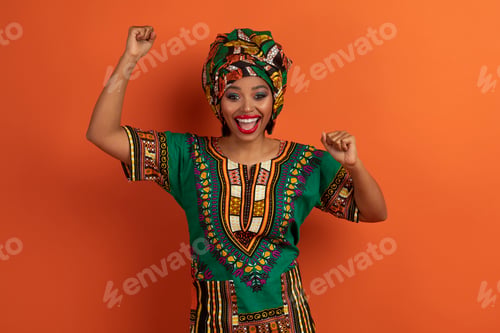 Preview: Super happy young african lady celebrating success win on orange