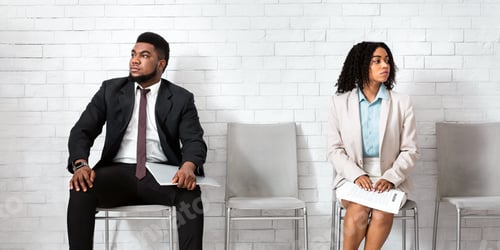 Preview: Black man and woman looking in opposite directions, feeling competitive while waiting for job