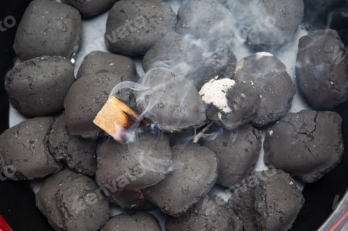 Preview: a man lights a fire with a lighter special charcoals for a barbecue