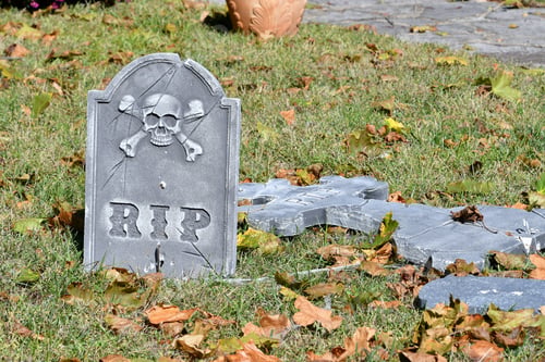 Preview: A tombstone with RIP and a skull and crossbones on it as a Halloween decoration in a yard