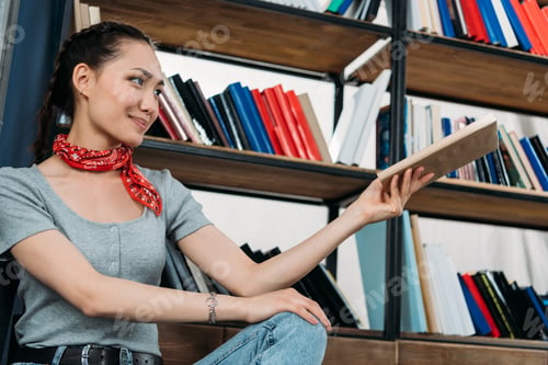 Preview: young asian woman smiling and holding book at home library