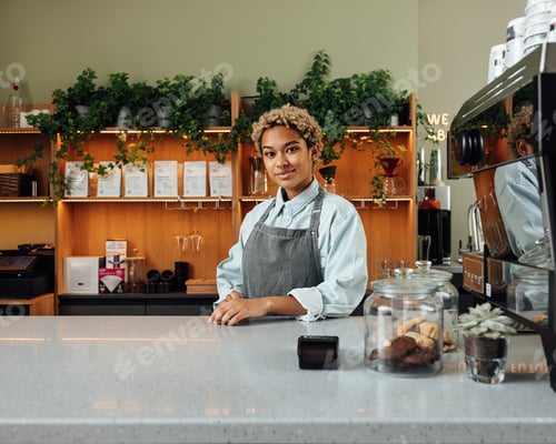 Preview: Portrait of a young and confident coffee shop owner at the counter looking at camera