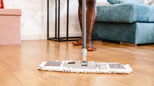 Preview: Unrecognizable man cleaning the floor of his house with a mop.