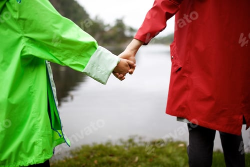 Preview: Close up mother holding daughter hand by lakeside