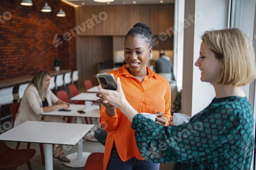Preview: Two Women Standing Together Looking at Cell Phone