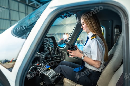 Preview: Female pilot preparing headset in cockpit of small airplane