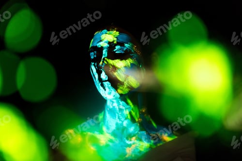 Preview: model with colorful neon paints on body posing on black backdrop