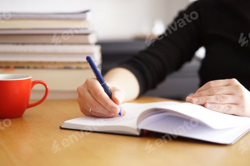 Preview: Closeup shot of a woman working or studying from home with a red coffee cup nearby