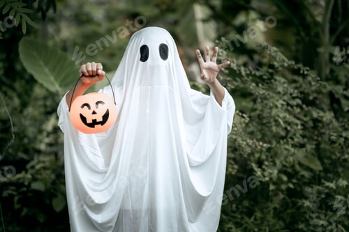 Preview: A young boy dressed as a ghost for Halloween wears a white sheet with black eye holes