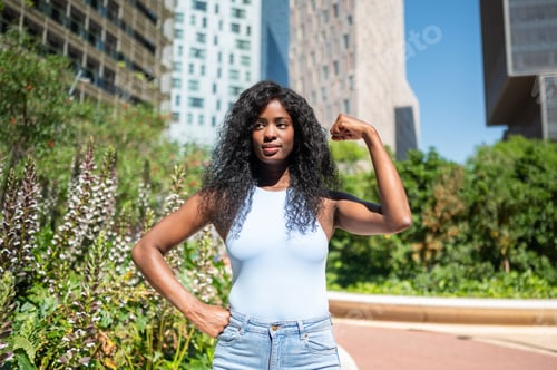 Preview: Strong black woman flexing biceps in urban park setting