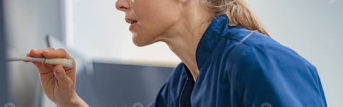 Preview: Nurse on Duty makes announcement into microphone sitting at Reception Desk in modern clinic