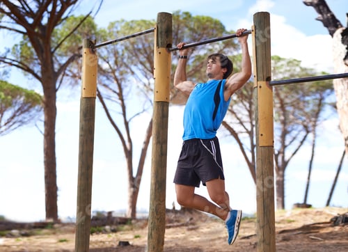 Preview: Determination is everything. Young adult male using outdoor gym apparatus.