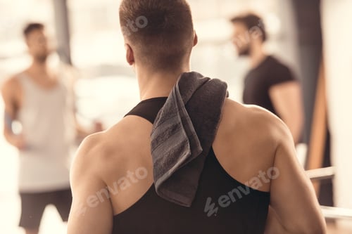 Preview: back view of muscular sportsman with towel on shoulder
