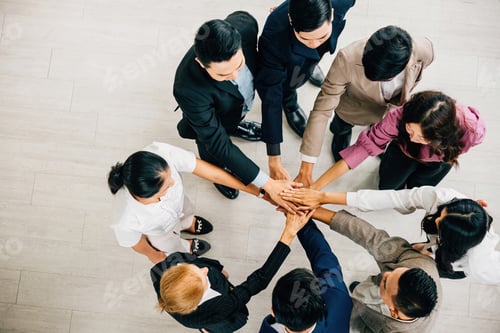 Preview: Four diverse business professionals hold hands in a circle from a top view forming a symbolic stack