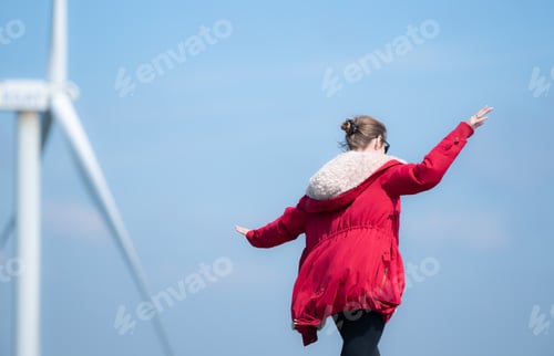 Preview: On the background of windmills, A young woman in a red jacket is enjoying her winter vacation.