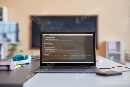 Preview: Laptop with coded data on screen standing on desk with headphones