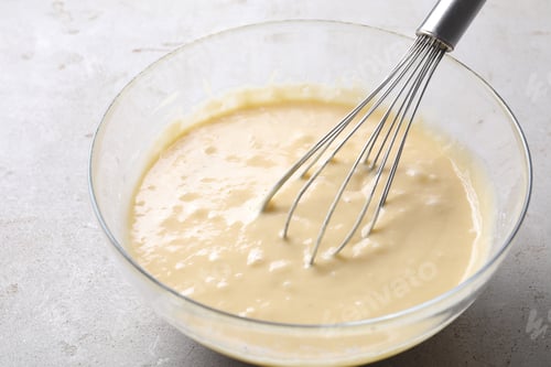 Preview: Whisk and bowl of dough on grey table, closeup