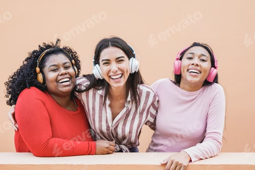 Preview: Young latin women having fun together outdoor in the city while wearing headphones