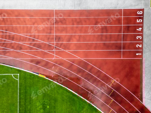 Preview: Aerial view of a red running track with marked lanes and curved lines.