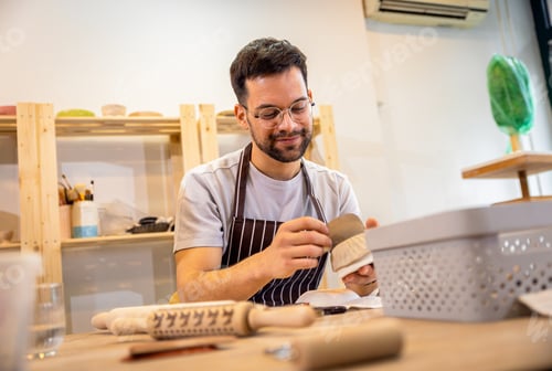 Preview: Man working in pottery studio workshop making bowl from clay.