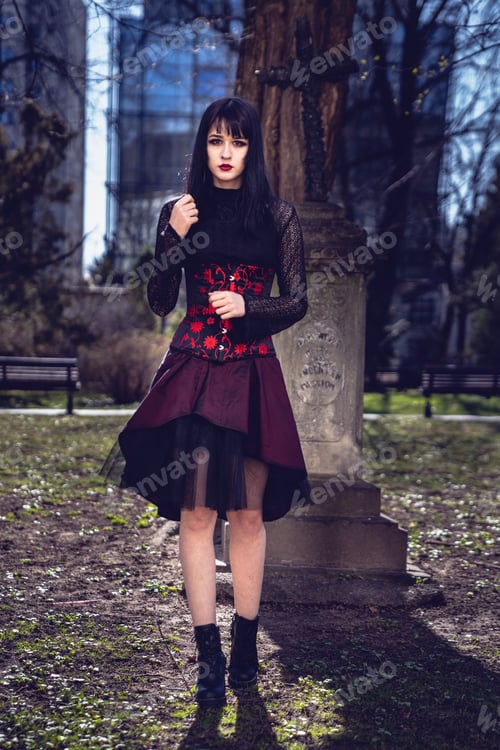 Preview: Vertical shot of a Caucasian pretty female in a gothic style black and red dress