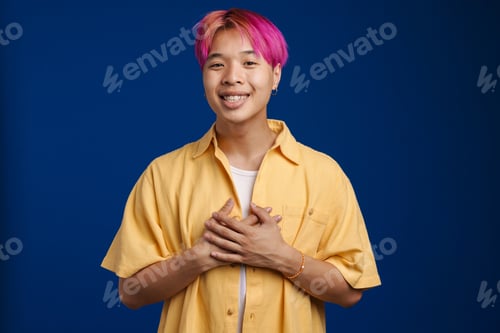 Preview: Asian boy with pink hair smiling while holding hands on his chest