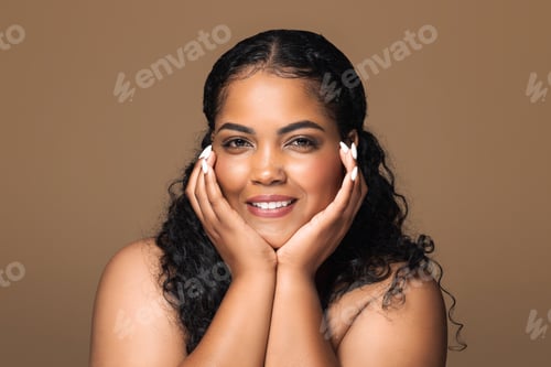 Preview: Face care concept. Beautiful brazilian body positive woman with curly hair touching face with