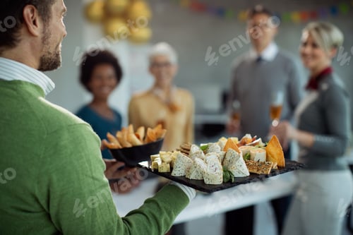 Preview: Close-up of businessman serving food during office party.