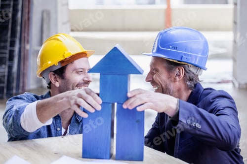 Preview: Two happy men with hard hats and model house