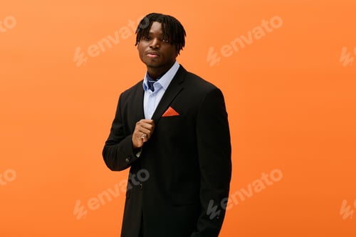 Preview: Stylish young man poses confidently against a vibrant orange backdrop
