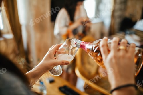 Preview: Close up of woman pouring Champagne in a glass.