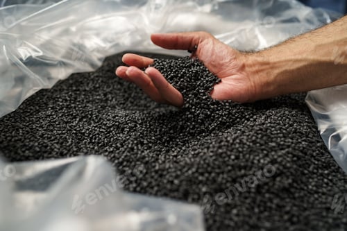 Preview: Close up of male hand holding plastic polymer granules