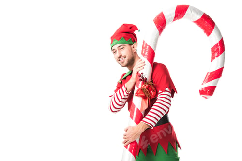 Preview: smiling man in christmas elf costume carrying big candy cane isolated on white